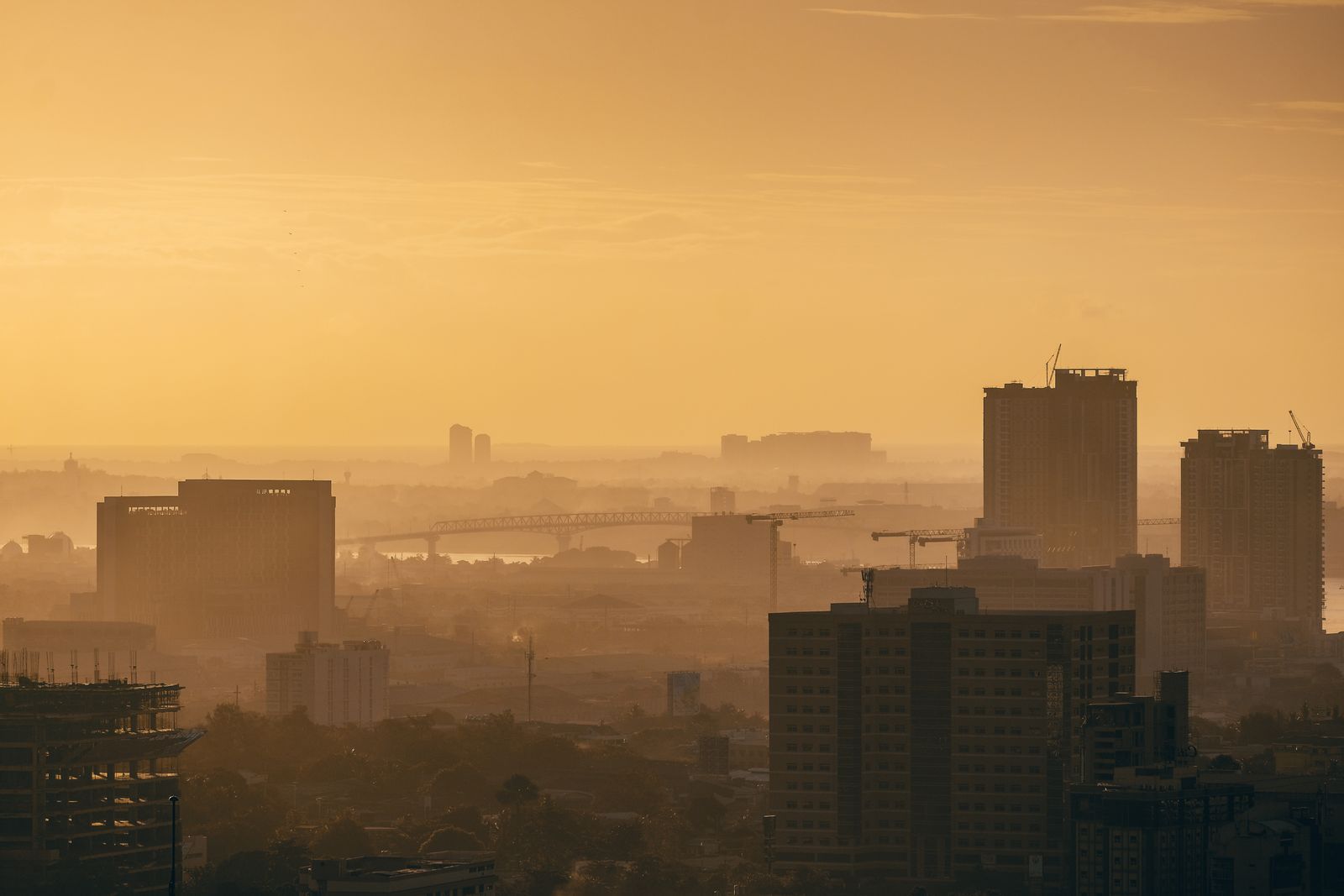 Cebu City skyline at golden hour, hazy amber light over the buildings, seen from above