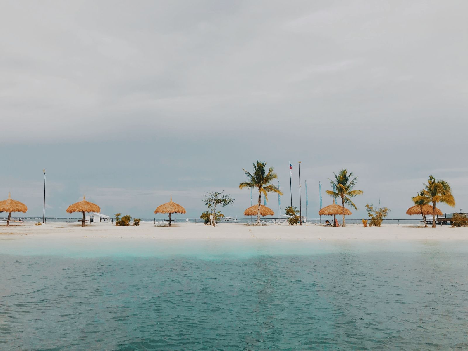 A row of nipa-hut beach cottages under palm trees on the shore in Lapu-Lapu City, Mactan