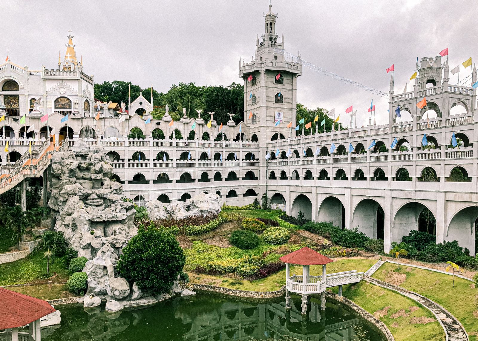 The castle-like towers and arched galleries of the Simala shrine in Sibonga, with gardens and banderitas in the courtyard