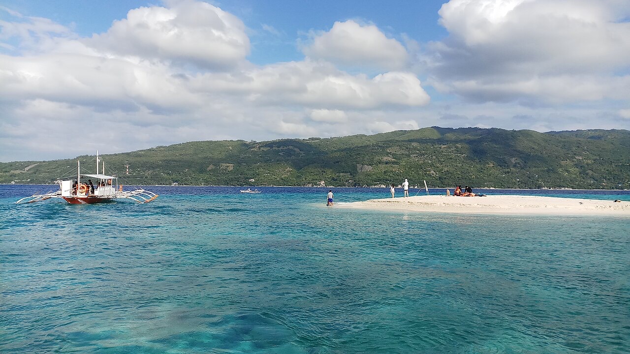 The white sandbar of Sumilon Island with a banca boat approaching